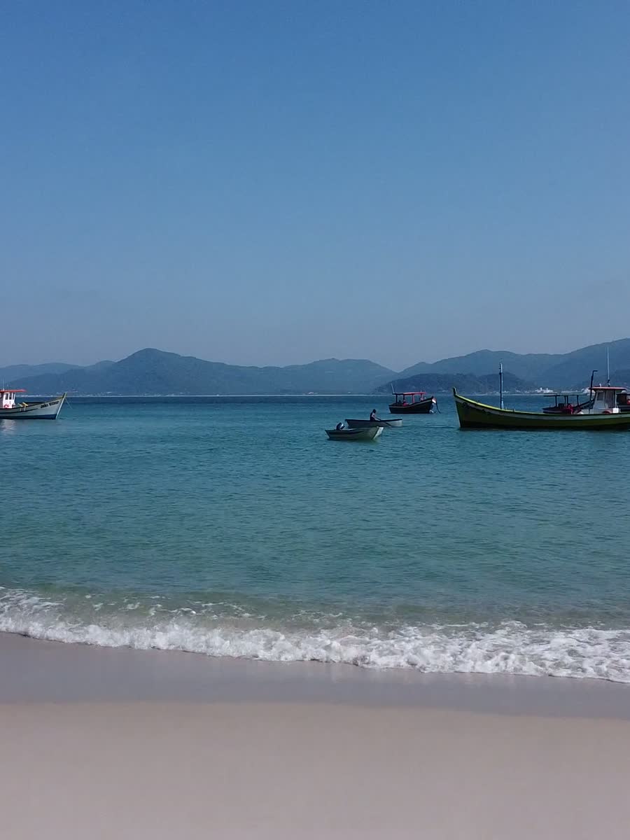Turquoise water and traditional fishing boats off a Florianópolis beach